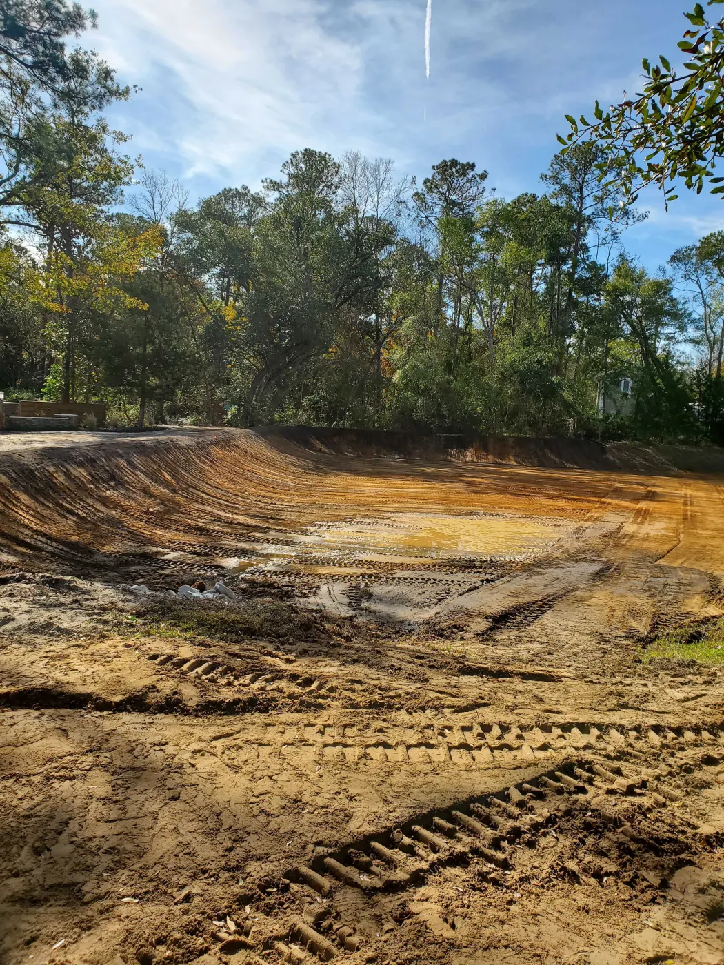 Wide drainage swale freshly cut in sandy soil with track marks during drainage and culvert installation near Burgaw, NC