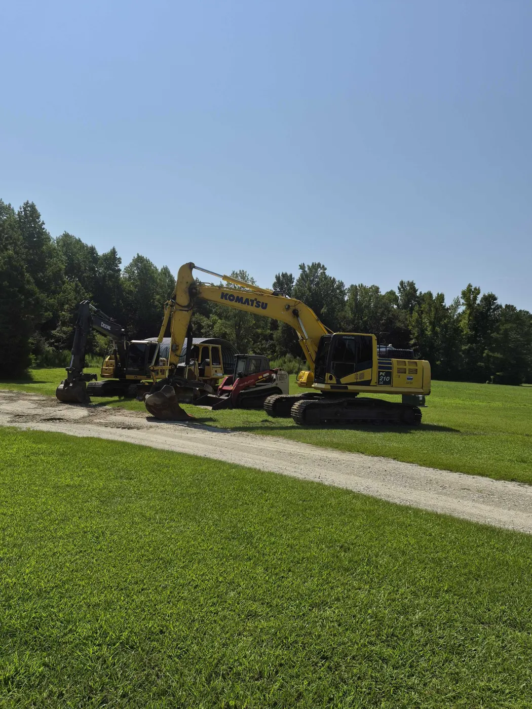 Coastal Brush Mowing excavators staged on a green field near Burgaw, NC