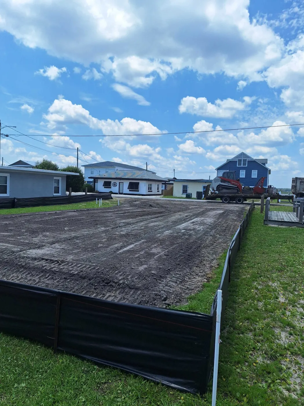 Graded lot with black silt fence for erosion control after yard drainage regrading in front of homes in Pender County, NC