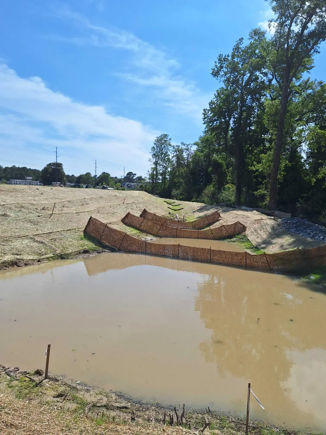 Excavator shaping the bank of a new farm pond on sandy ground in Pender County North Carolina