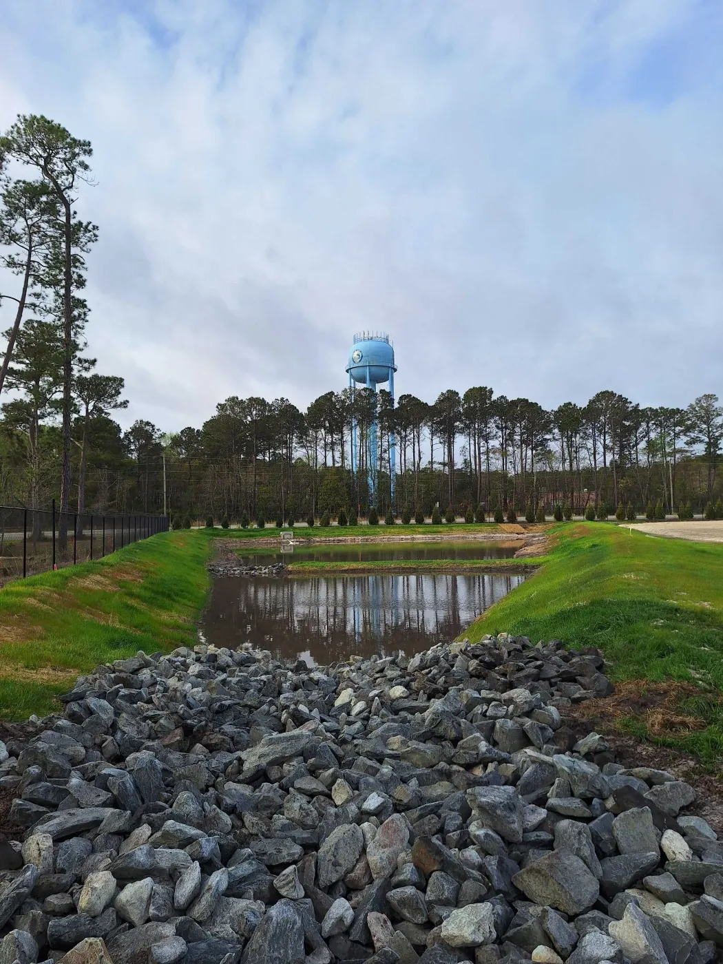 Finished retention pond with a rip-rap outlet on a commercial site in Pender County